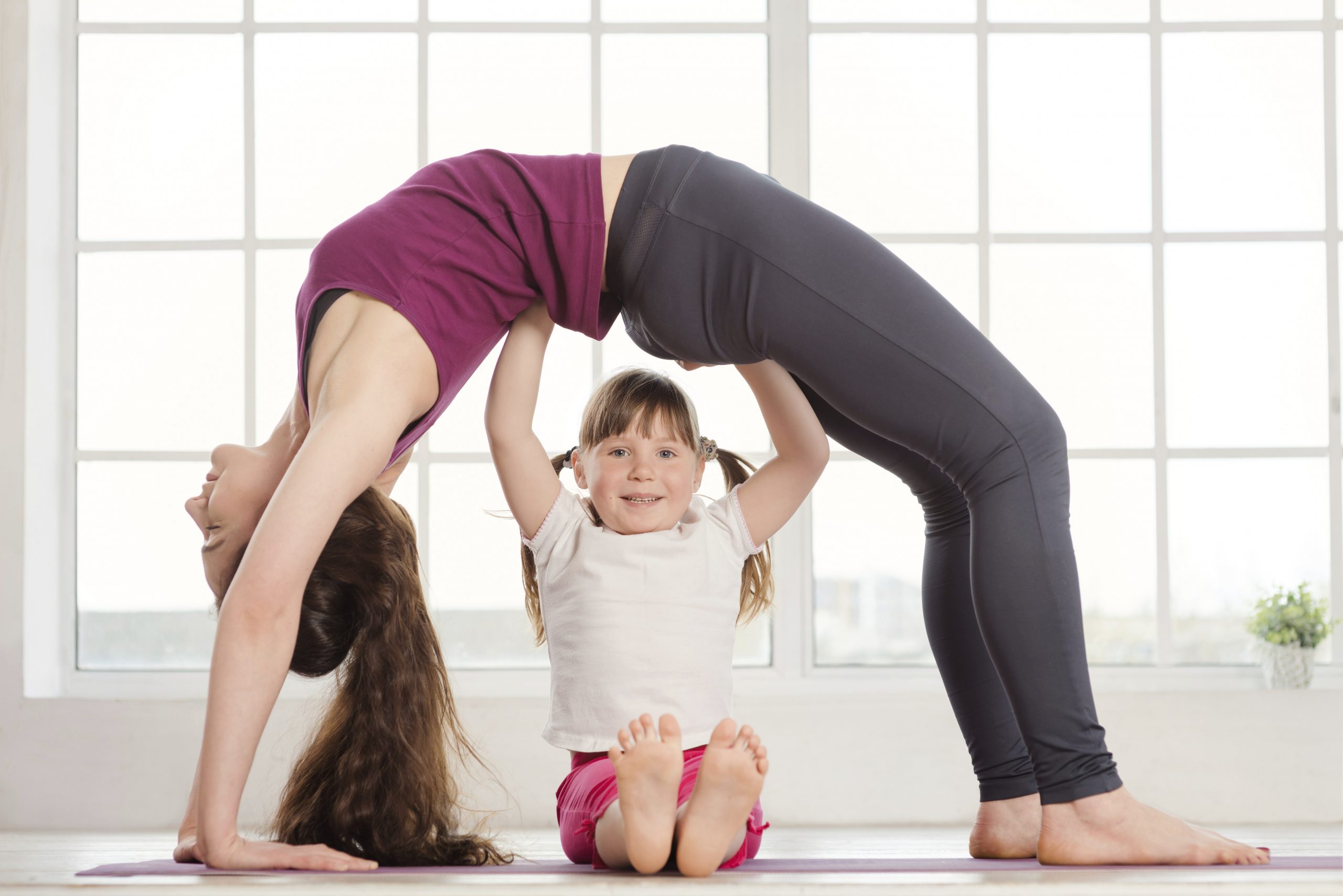 Young Mother And Daughter Doing Yoga Exercise